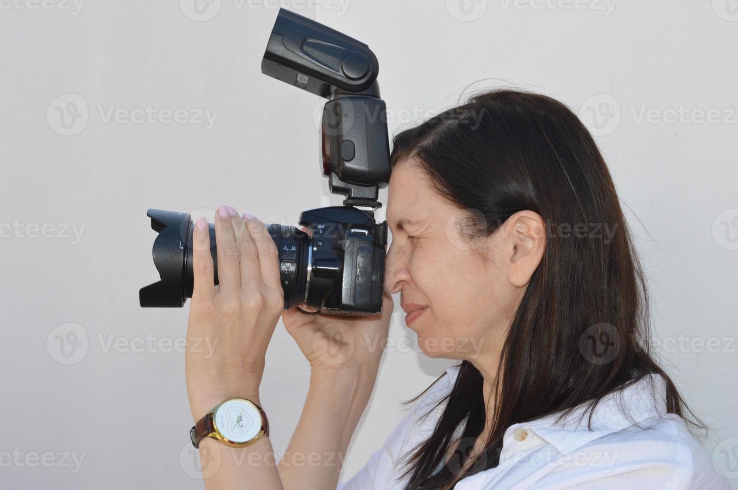 mulher morena é uma fotógrafa profissional com uma câmera. Vista de perfil. foto