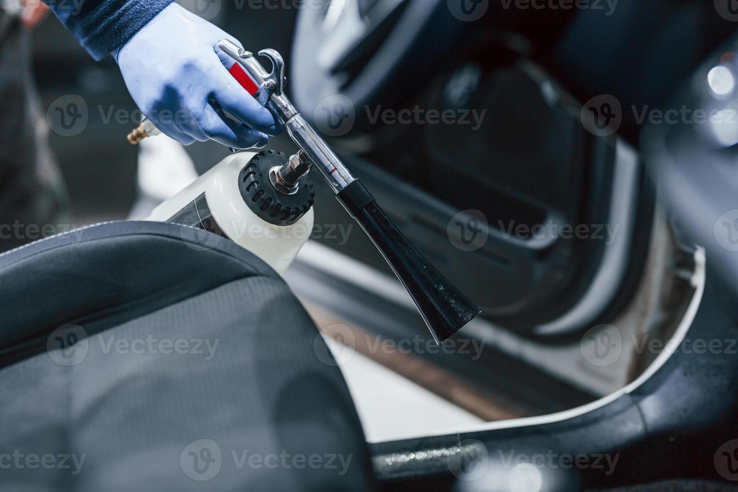 trabalhador masculino uniforme limpando carro novo e moderno. concepção de serviço foto