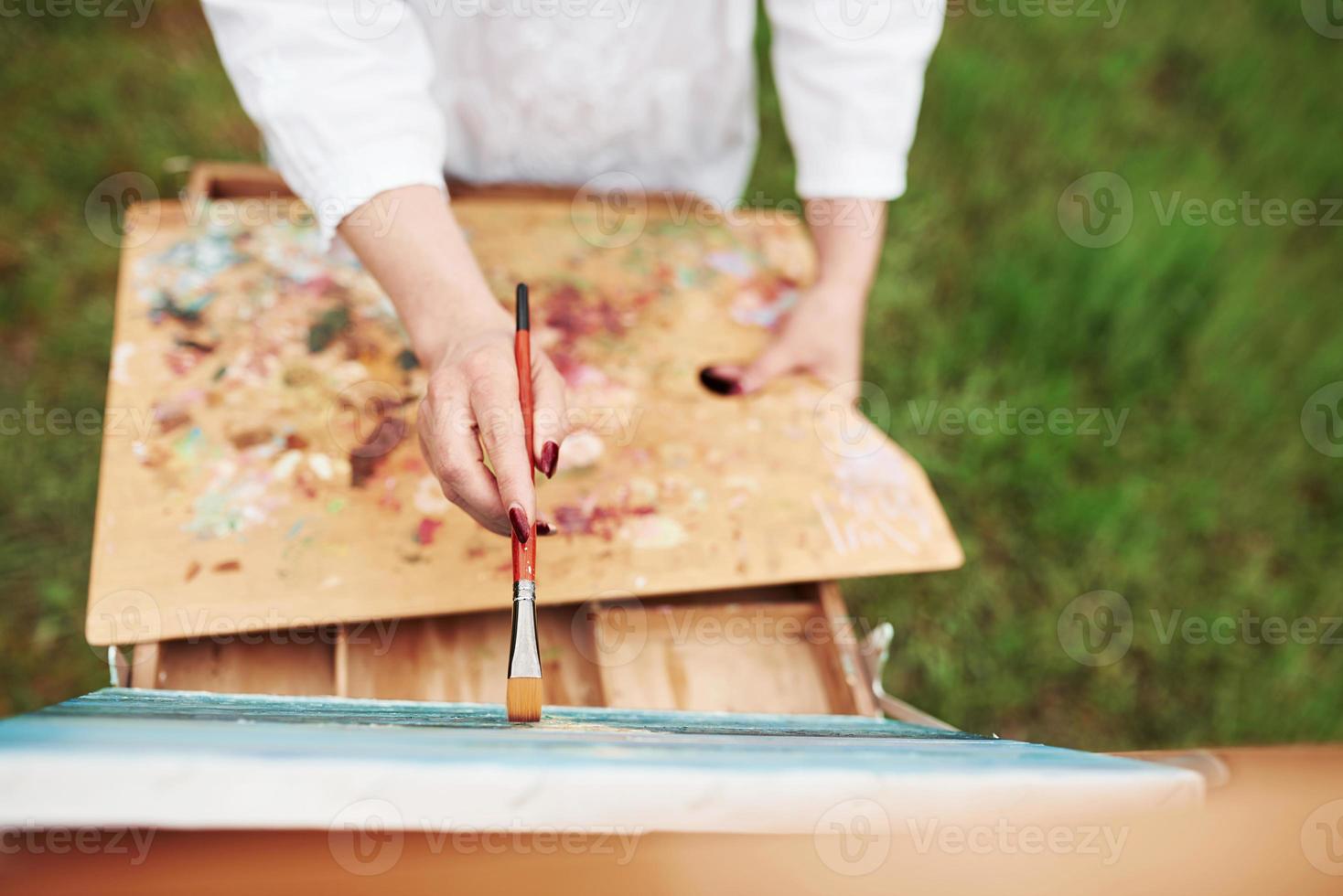 concepção da pintura. foto da mão de uma mulher com pincel vermelho