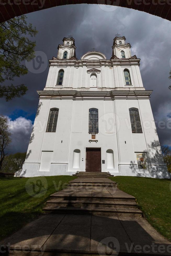 uma igreja católica branca em um dia de verão com nuvens escuras ao fundo foto