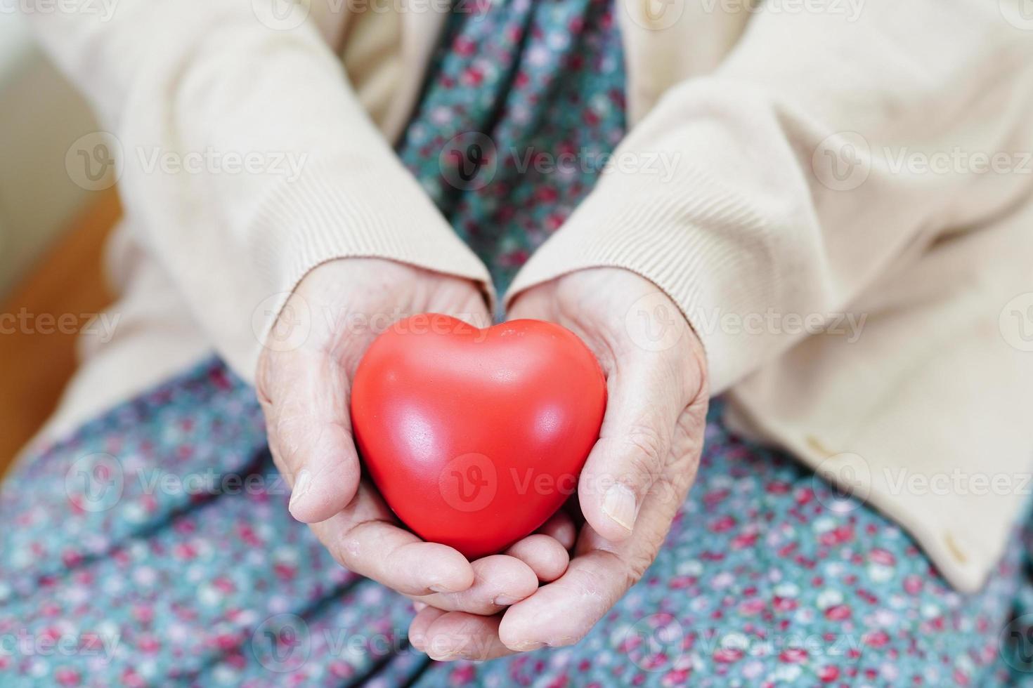 paciente asiática idosa idosa segurando coração vermelho no hospital. foto