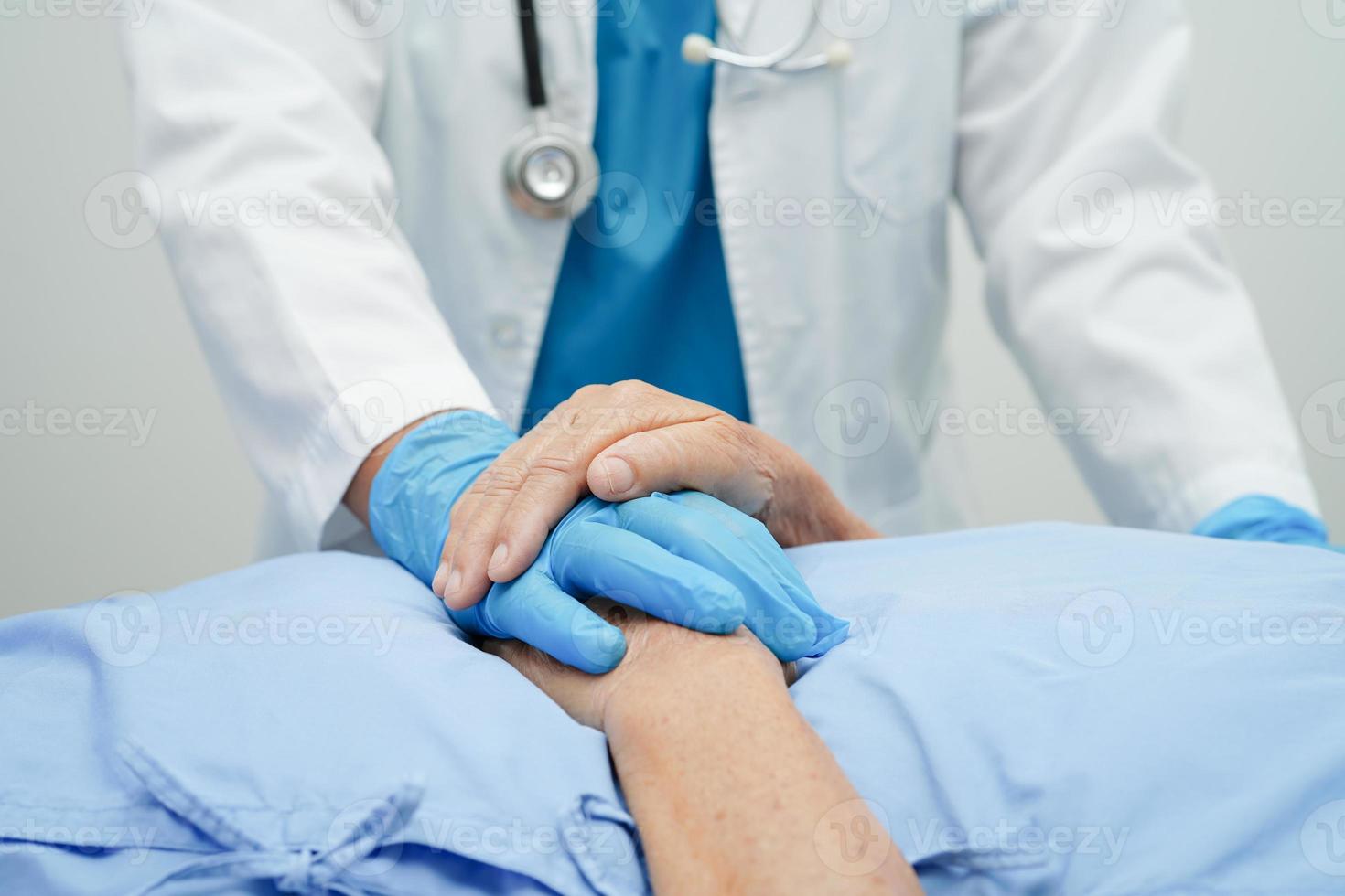 médico de mãos dadas paciente idosa asiática, ajuda e cuidados no hospital. foto