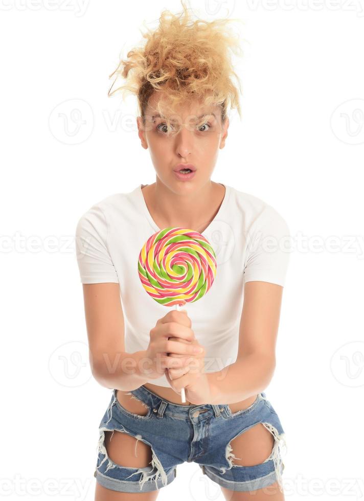 mulher loira lambendo doces. modelo feminino comendo delicioso pirulito de confeitaria com expressão de surpresa. foto