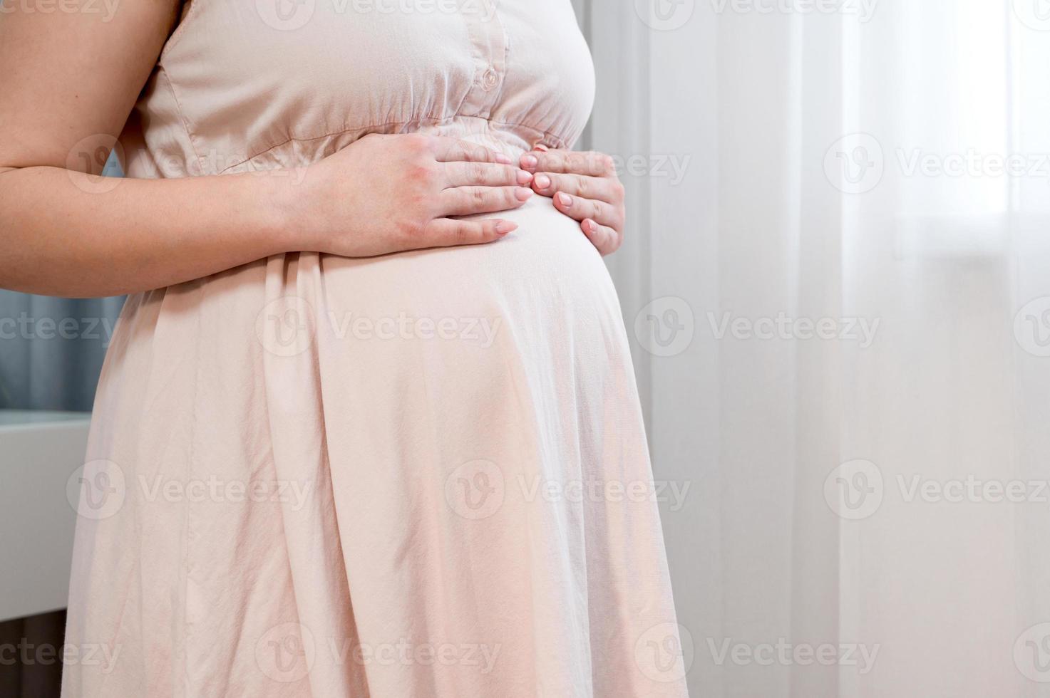 close-up da mulher grávida com barriga grande na janela conceito de gravidez, maternidade e expectativa foto