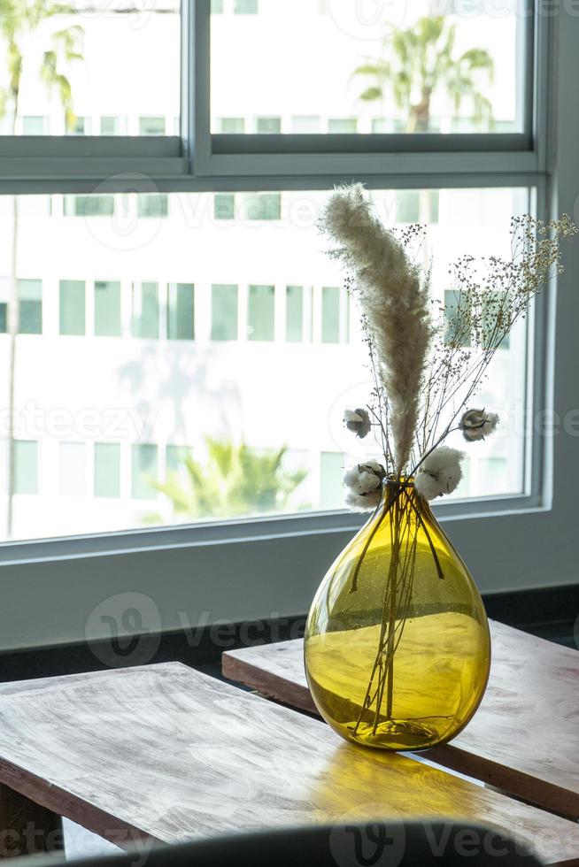 elegante moderno arranjo de flores secas em um vaso de vidro com fundo marrom. foto