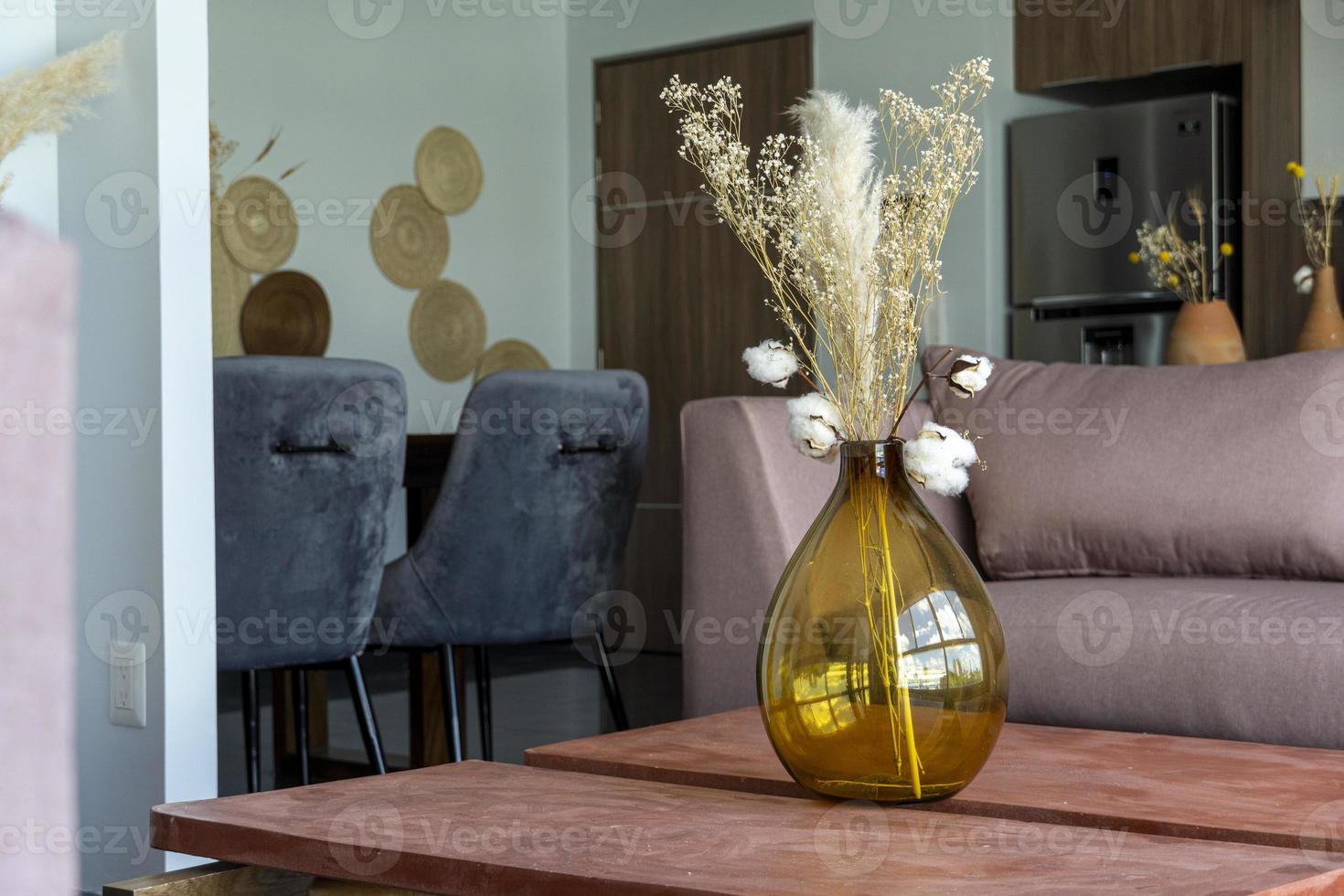 elegante moderno arranjo de flores secas em um vaso de vidro com fundo marrom. foto