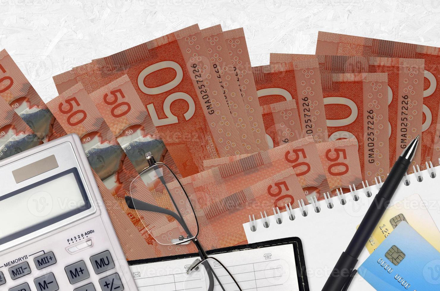 Notas de 50 dólares canadenses e calculadora com óculos e caneta. conceito de pagamento de impostos ou soluções de investimento. planejamento financeiro ou papelada do contador foto