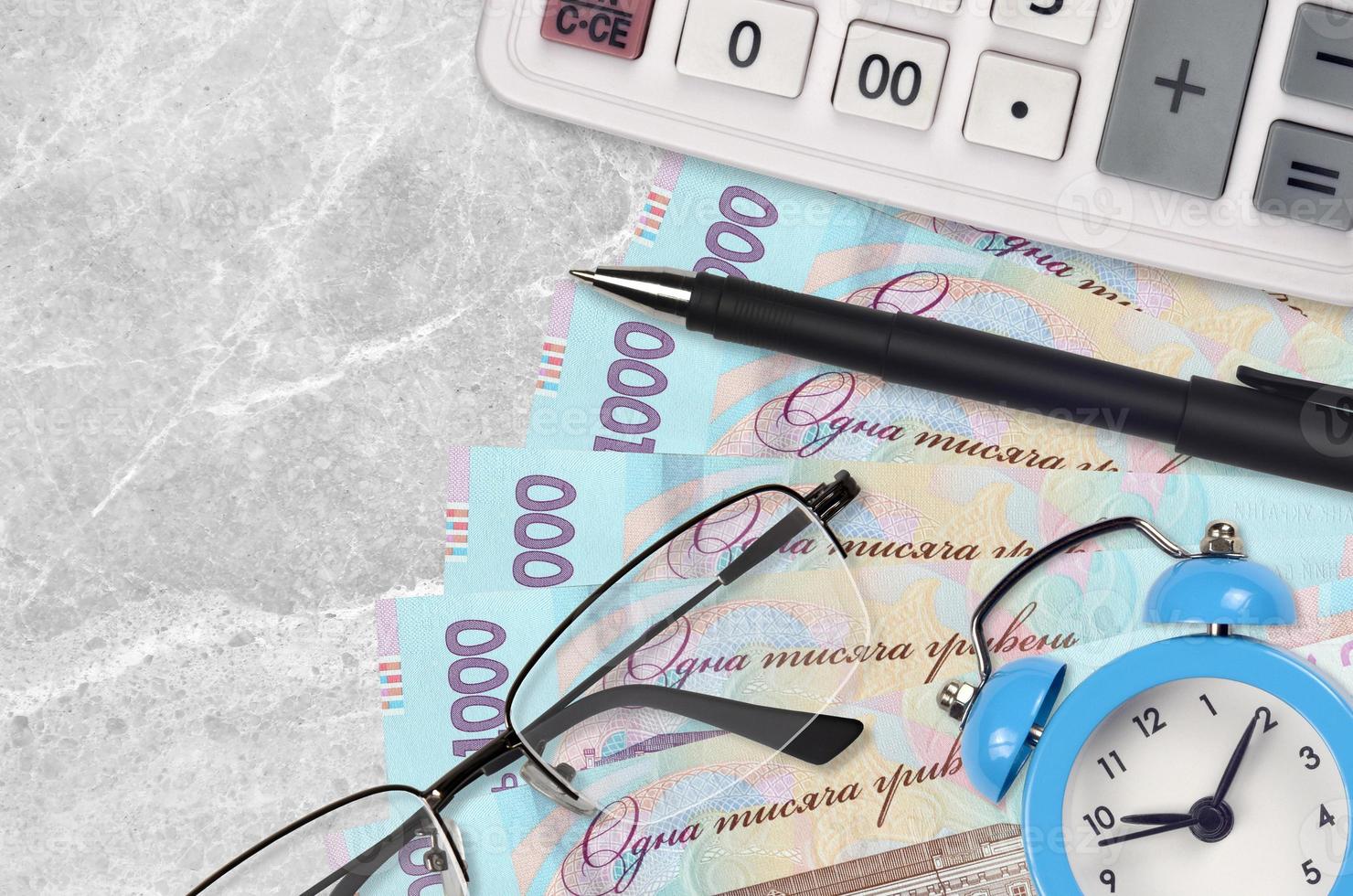 Notas de 1000 hryvnias ucranianas e calculadora com óculos e caneta. empréstimo comercial ou conceito de temporada de pagamento de impostos. hora de pagar impostos foto