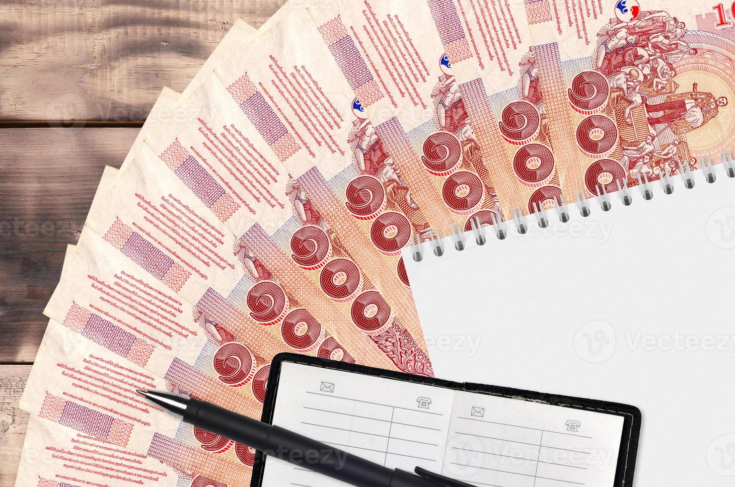 Ventilador de notas de 100 baht tailandês e bloco de notas com livro de contatos e caneta preta. conceito de planejamento financeiro e estratégia de negócios foto