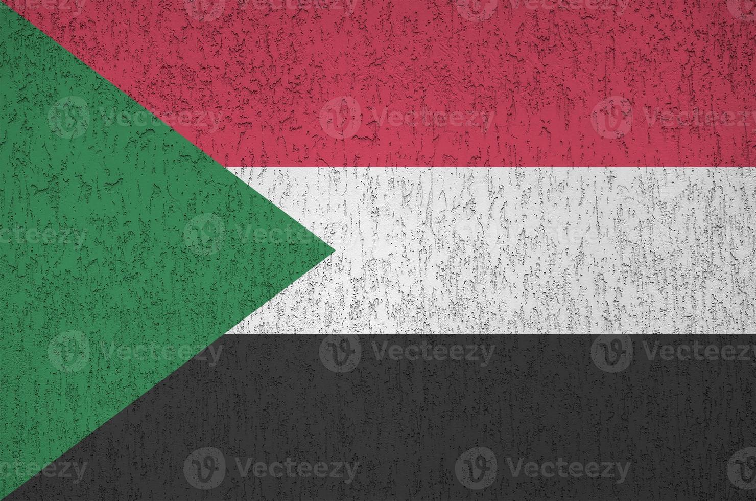 bandeira do sudão retratada em cores de tinta brilhante na parede de reboco em relevo antigo. banner texturizado em fundo áspero foto