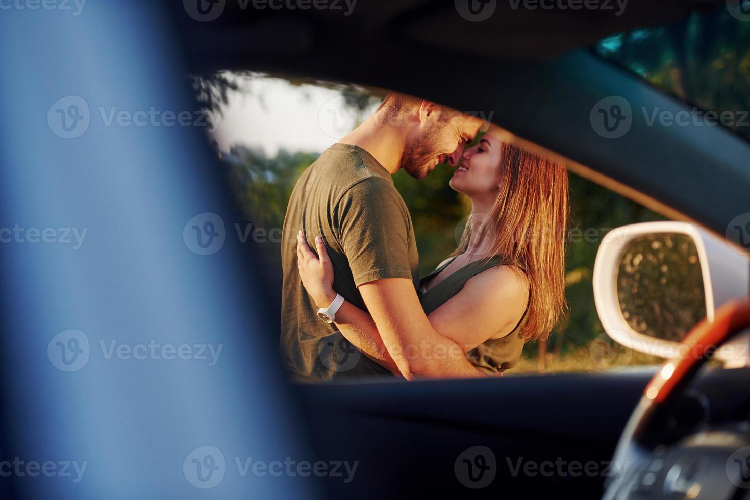 vista pela janela do carro. lindo casal jovem se diverte na floresta durante o dia foto