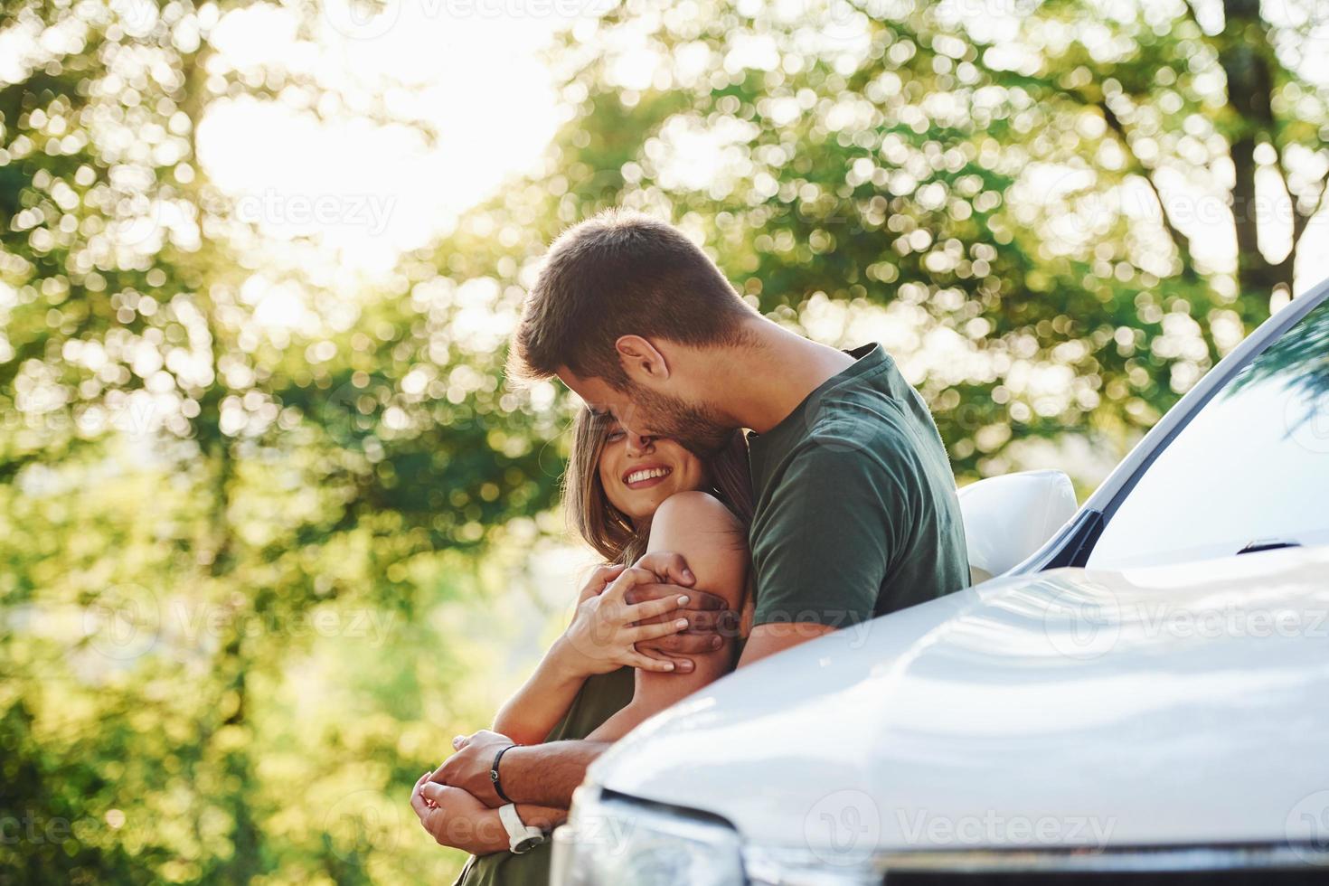 atrás do carro. lindo casal jovem se diverte na floresta durante o dia foto