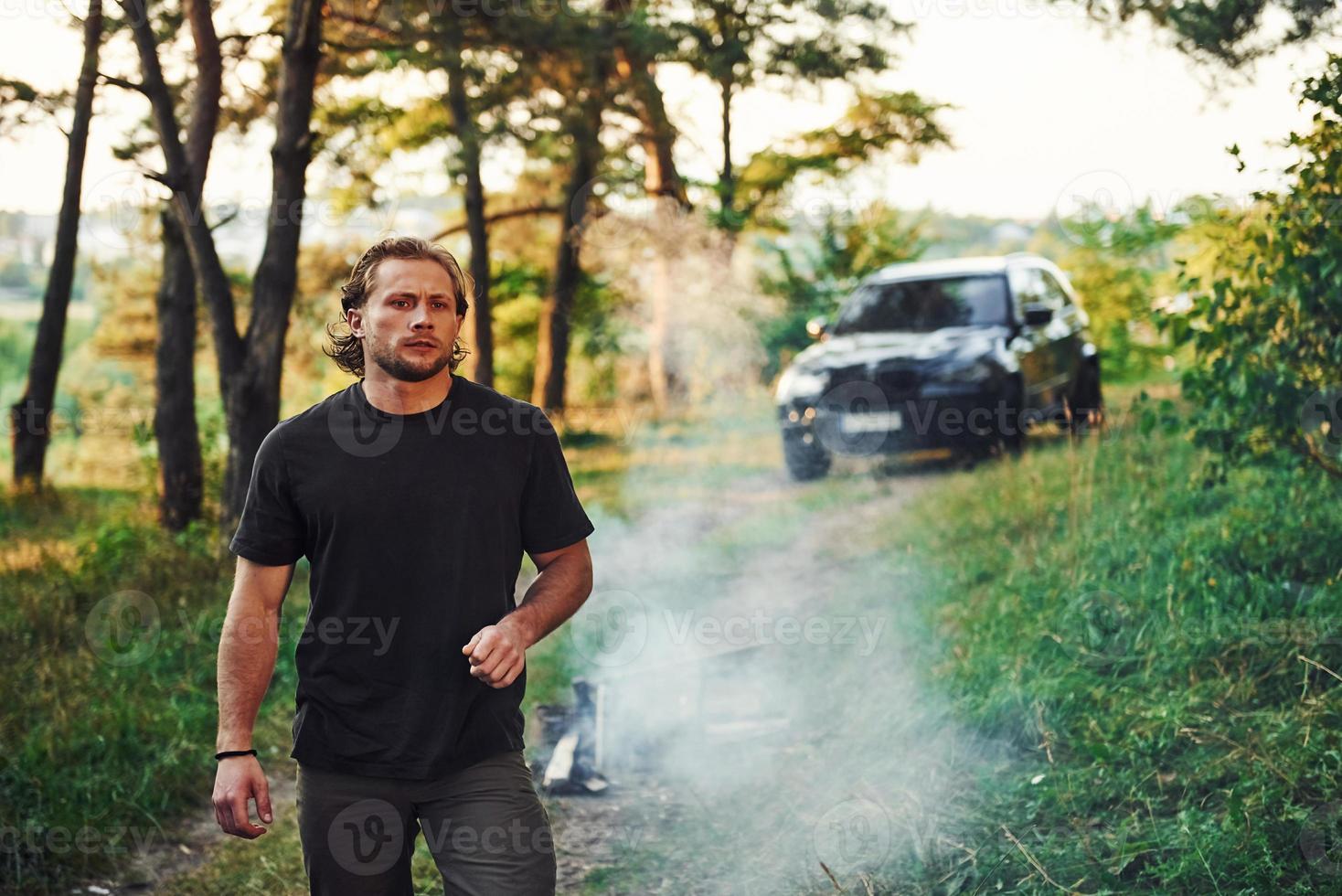 retrato do homem que fica na floresta e olha para a natureza. automóvel estacionado atrás foto