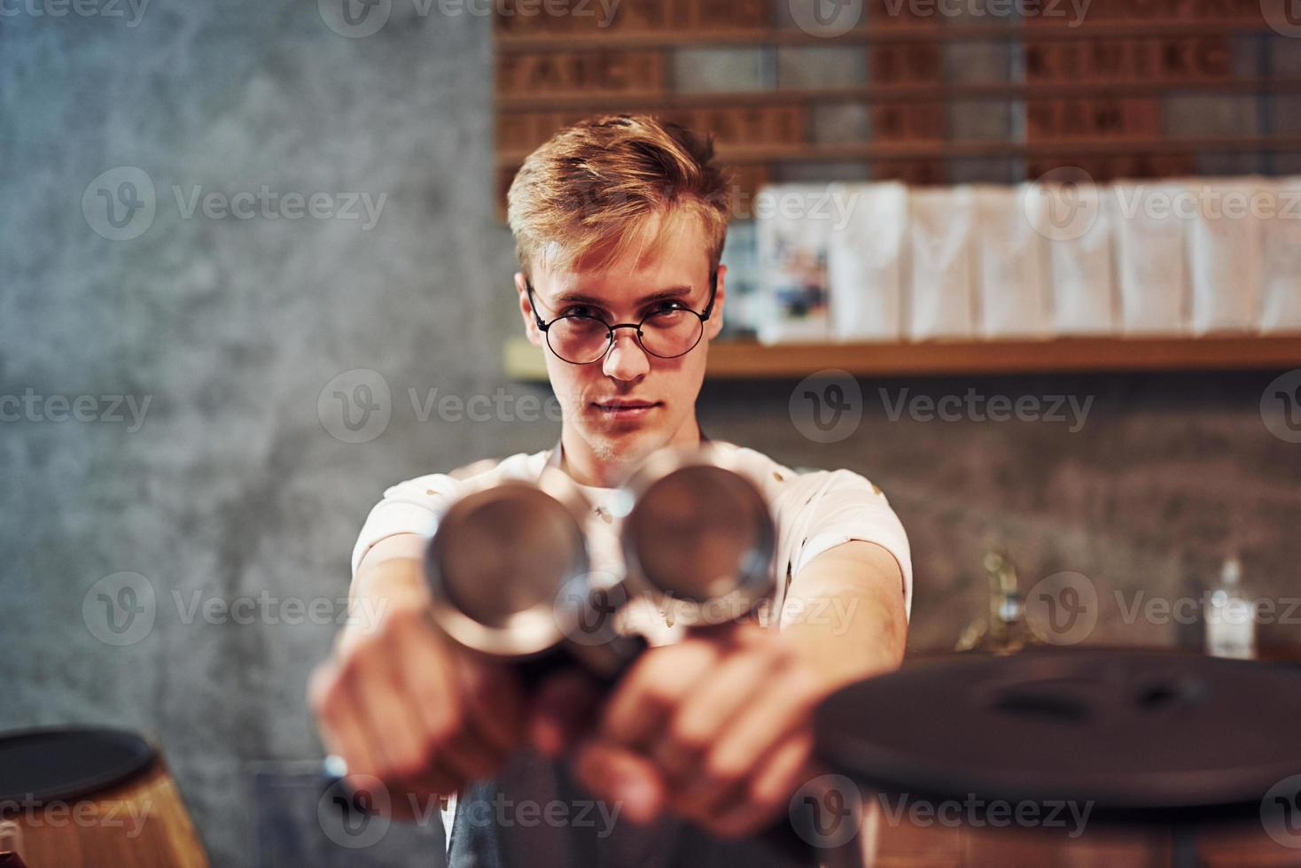 foto focada. trabalhador de café masculino jovem dentro de casa. concepção de negócio e serviço