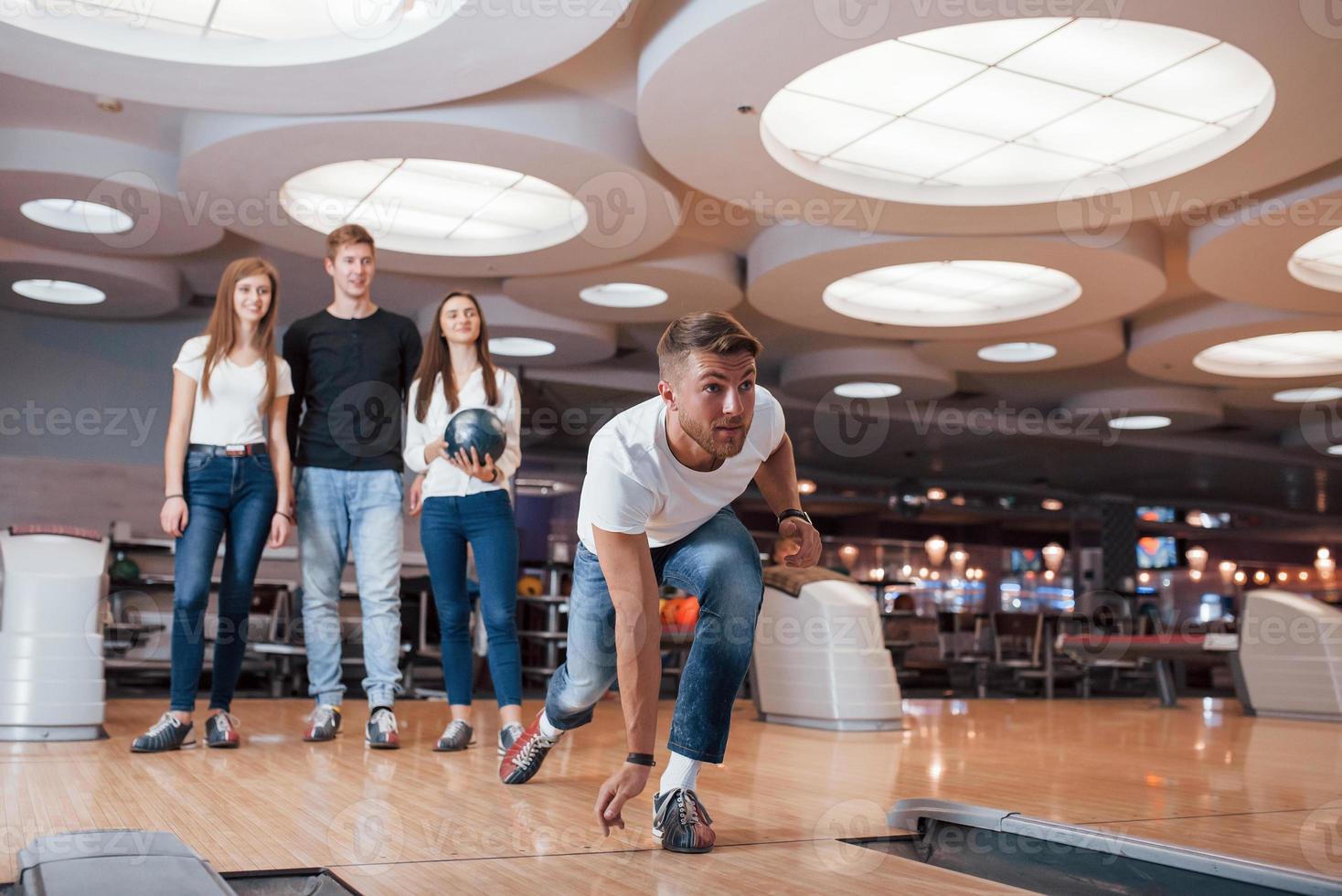 eu quero atacar. jovens amigos alegres se divertem no clube de boliche em seus fins de semana foto