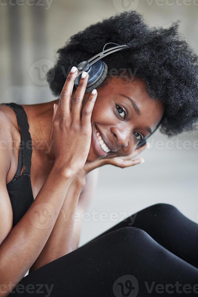 foto vertical. retrato de garota afro-americana em roupas de fitness tendo uma pausa após o treino