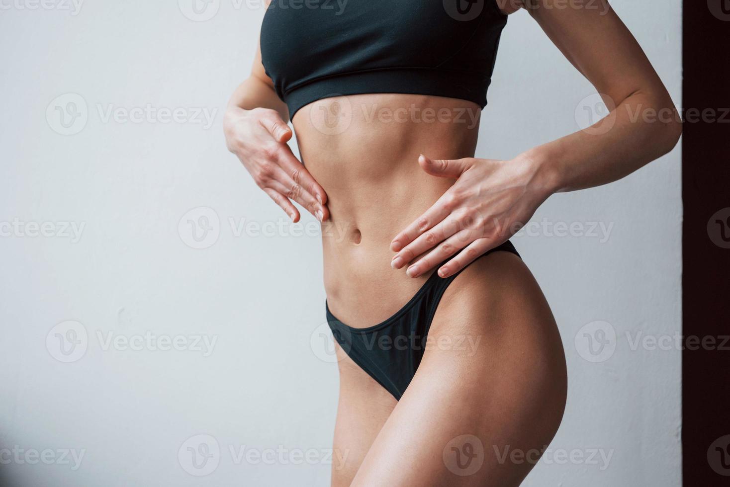 tocando a barriga. visão de partícula do tipo de corpo magro quente de garota que fica na sala foto