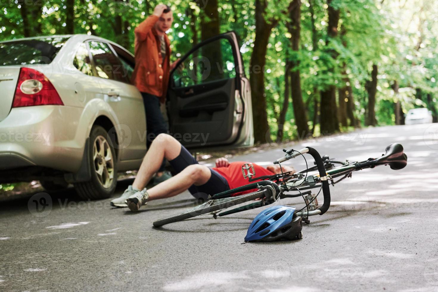 o que eu fiz. vítima no asfalto. bicicleta e acidente de carro prateado na estrada na floresta durante o dia foto