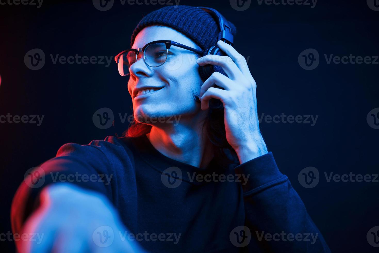 DJ em seu trabalho. studio filmado em estúdio escuro com luz neon. retrato de homem sério foto