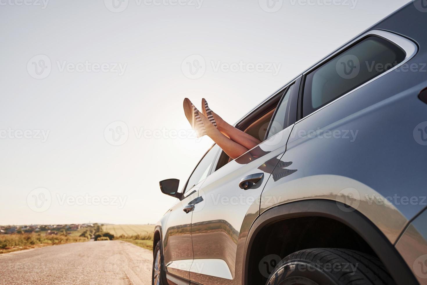 menina põe as pernas para fora na janela do automóvel no interior foto