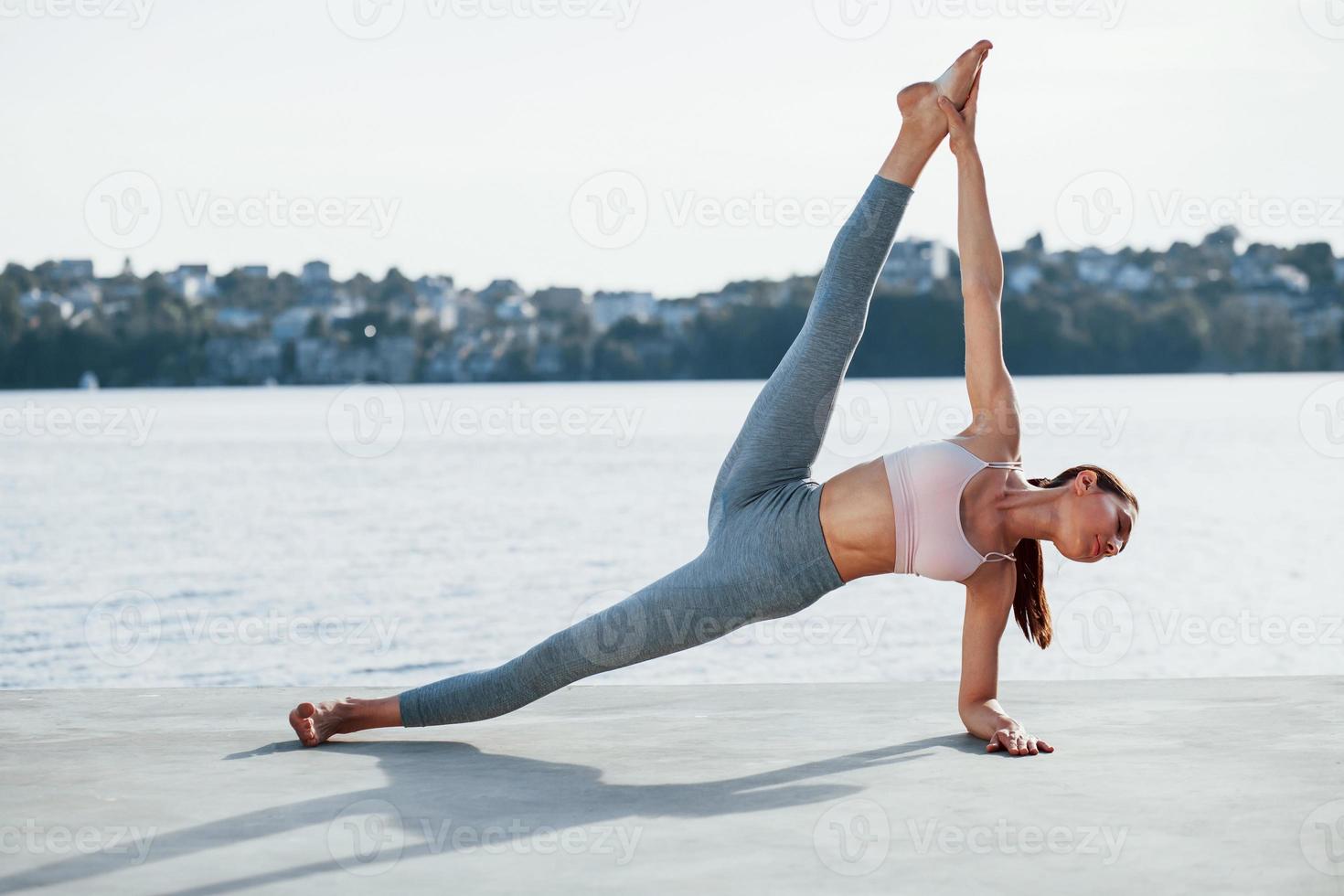 desfrutando do processo de treinamento. jovem com corpo magro faz exercícios contra o lago foto