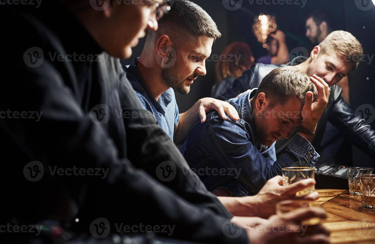 cara se sente horrível. amigos descansando no pub com álcool nas mãos. conversando foto