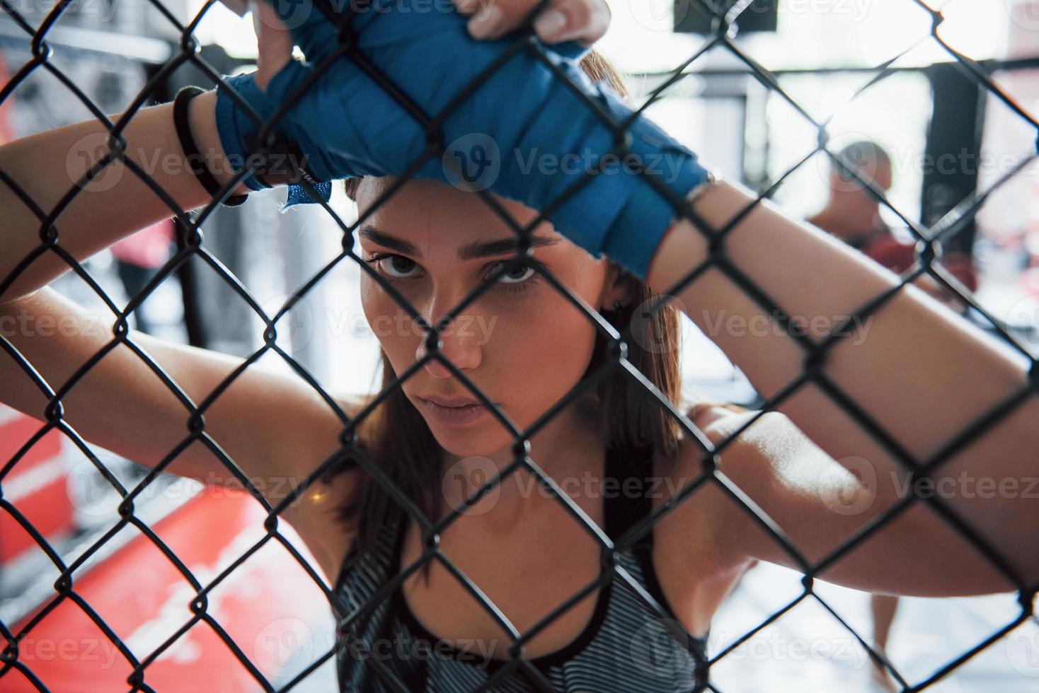 Tire uma folga. desportista no ringue de boxe tem exercício. encostado na cerca foto