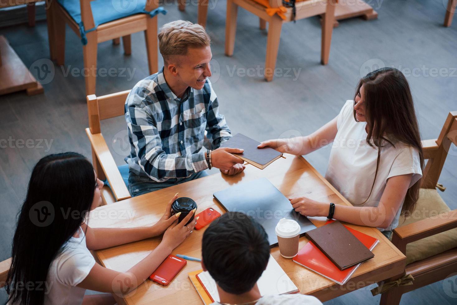 sentado no café e conversando. quatro jovens estudantes em roupas casuais se encontram em um dia chuvoso foto