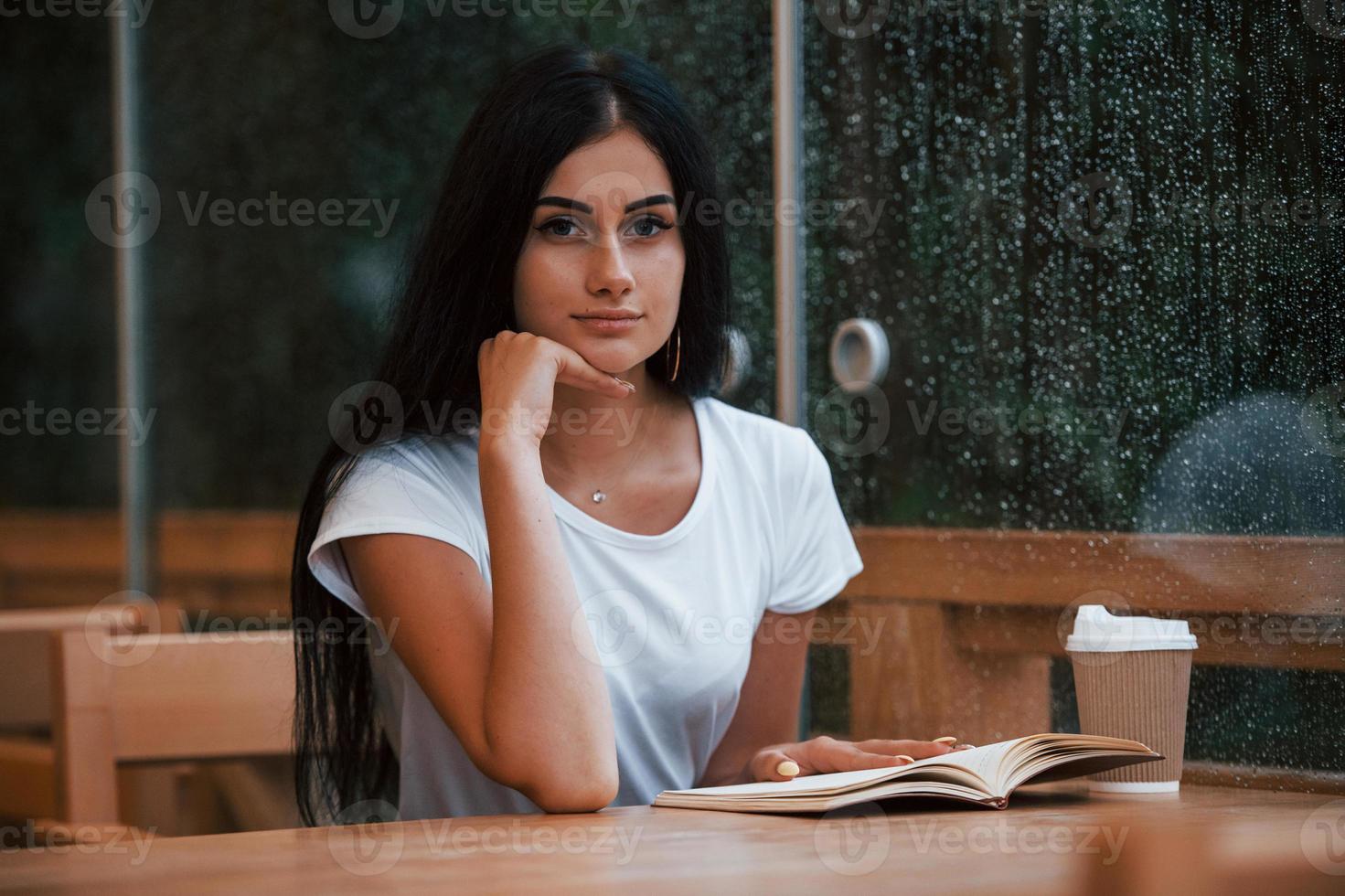 retrato de jovem aluna que se senta no café em dia chuvoso. uma pessoa só foto