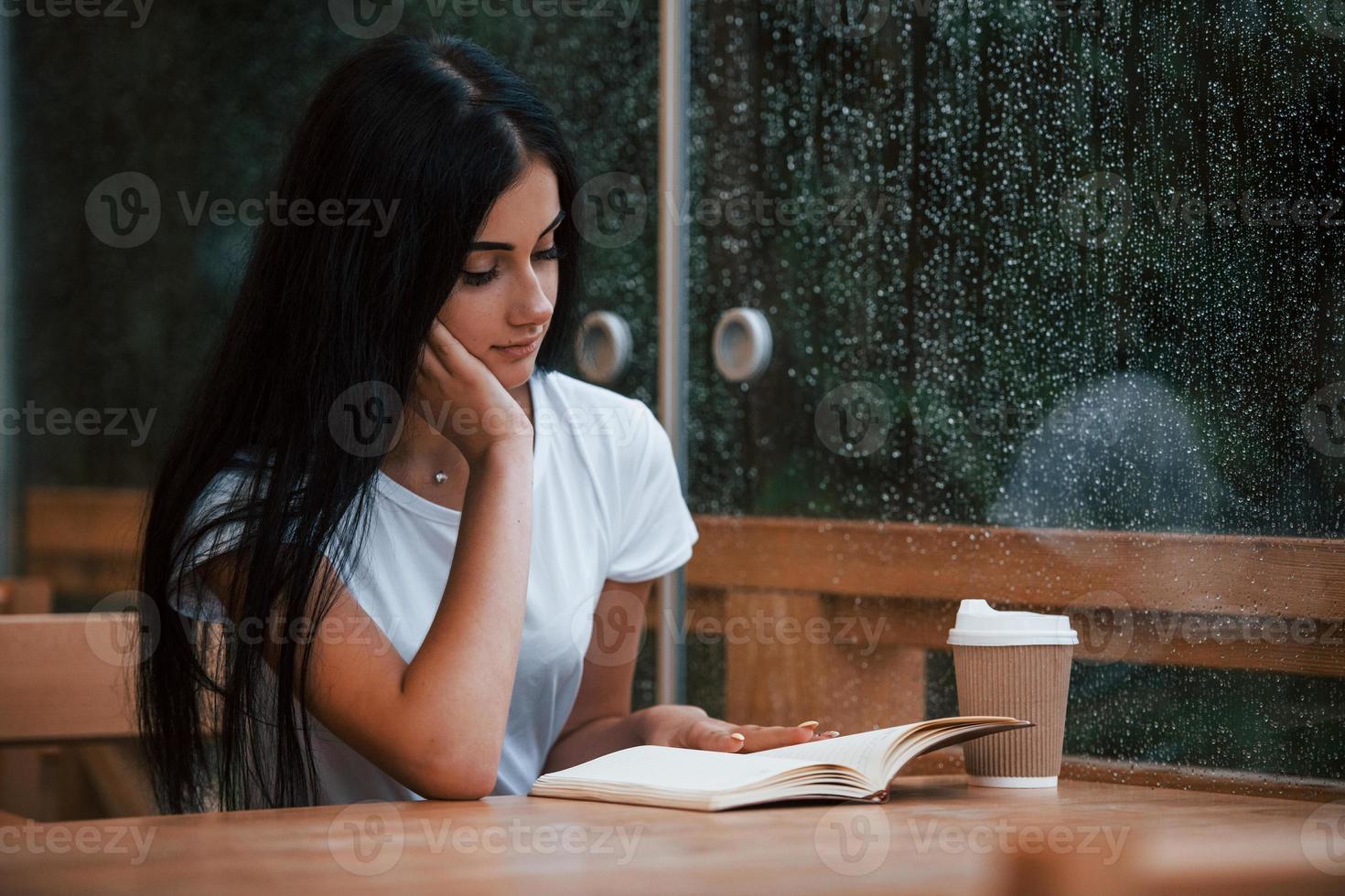 retrato de jovem aluna que se senta no café em dia chuvoso. uma pessoa só foto