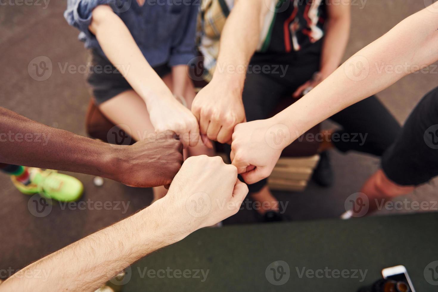 unidade das pessoas. grupo de jovens em roupas casuais faz uma festa no telhado juntos durante o dia foto