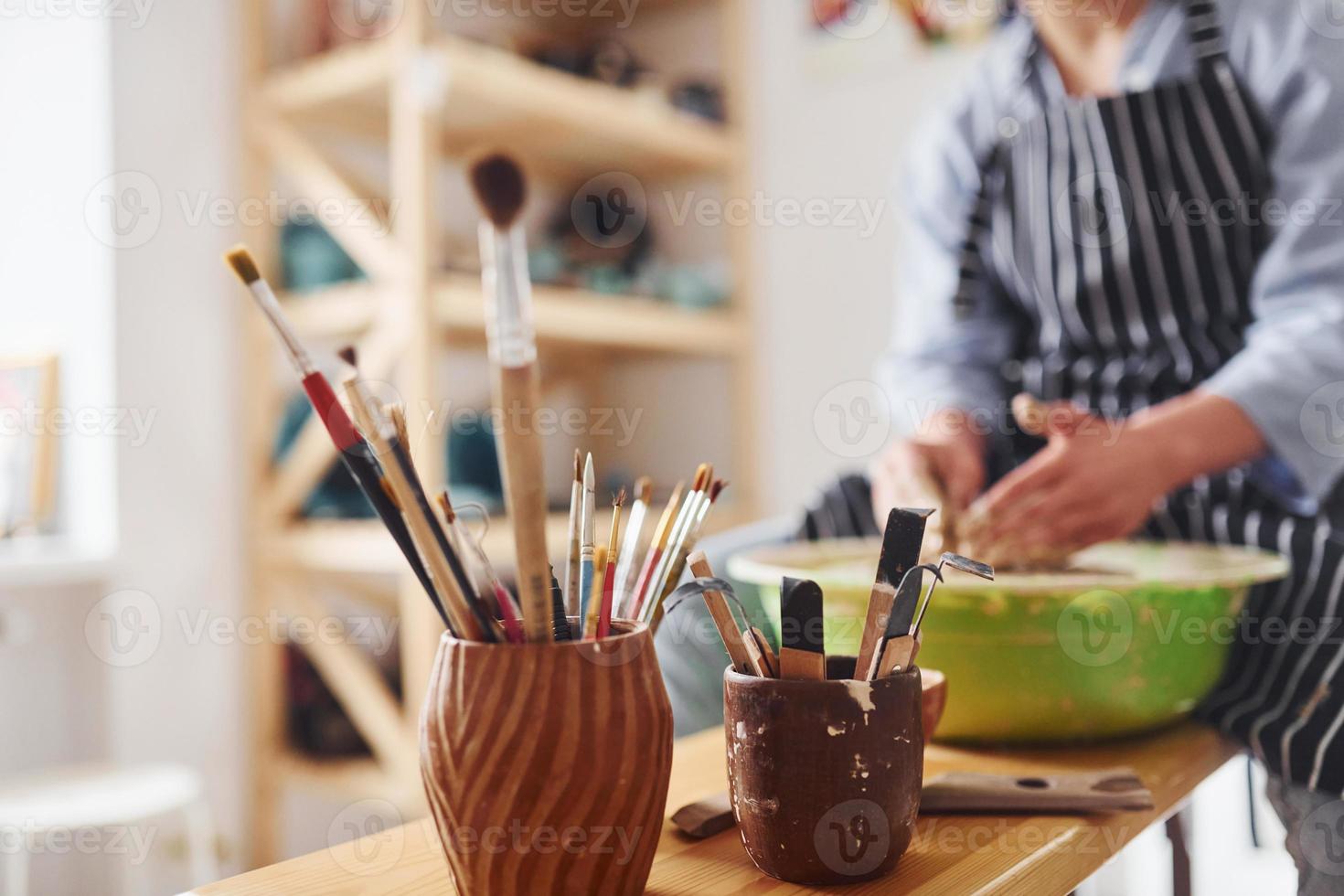 jovem ceramista feminina trabalhando usando roda de oleiro dentro de casa e fazendo produtos de argila feitos à mão foto