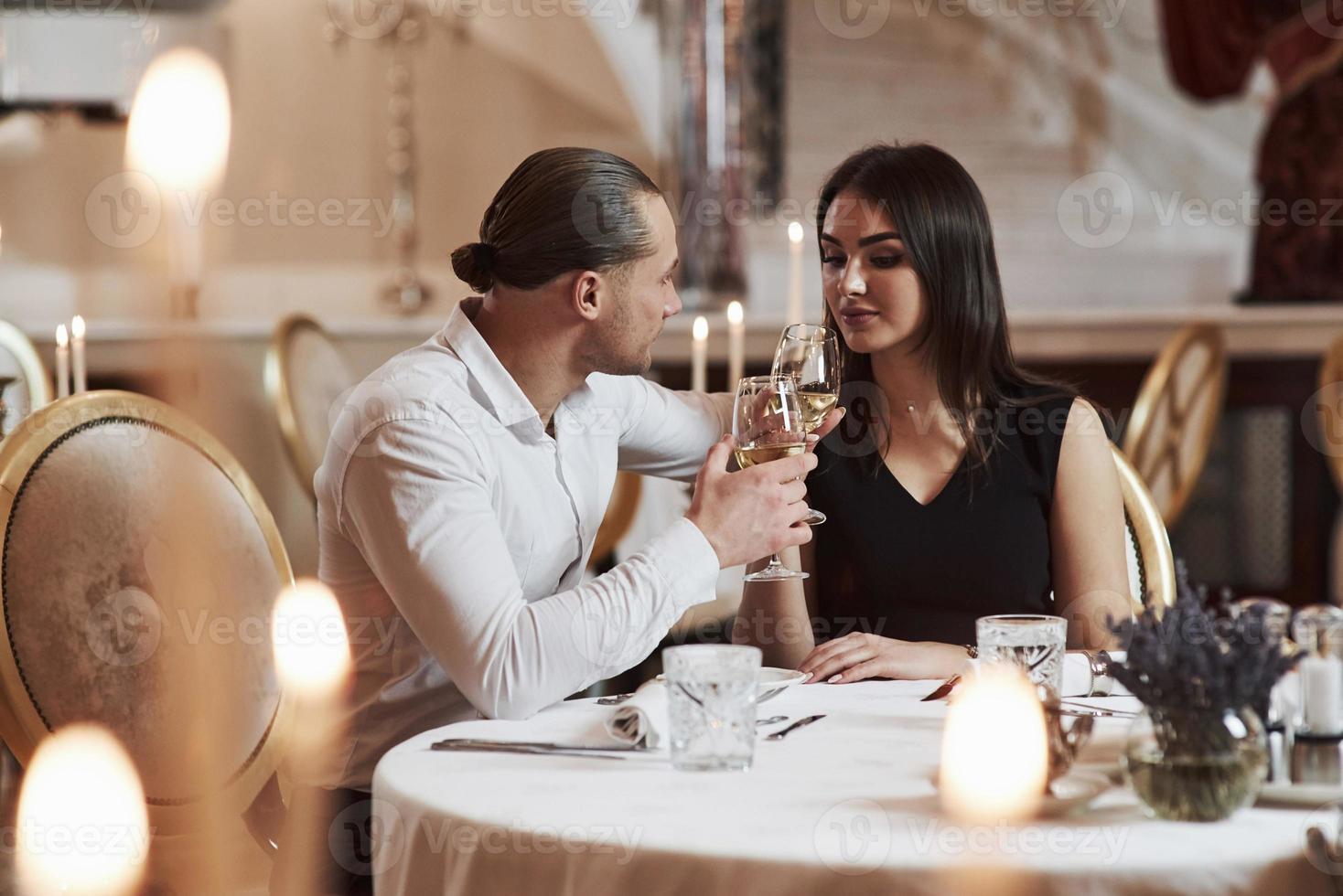 cara faz festa para a garota. lindo casal tem jantar romântico em restaurante de luxo à noite foto