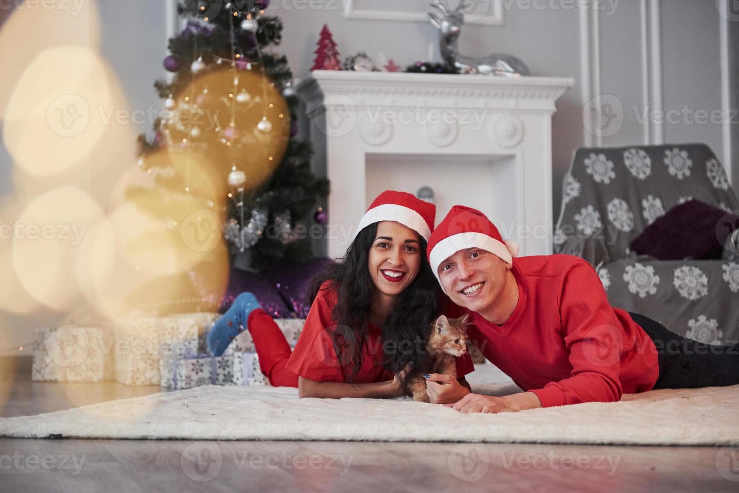 retrato de casal com gatinho comemora feriados em roupas de ano novo foto
