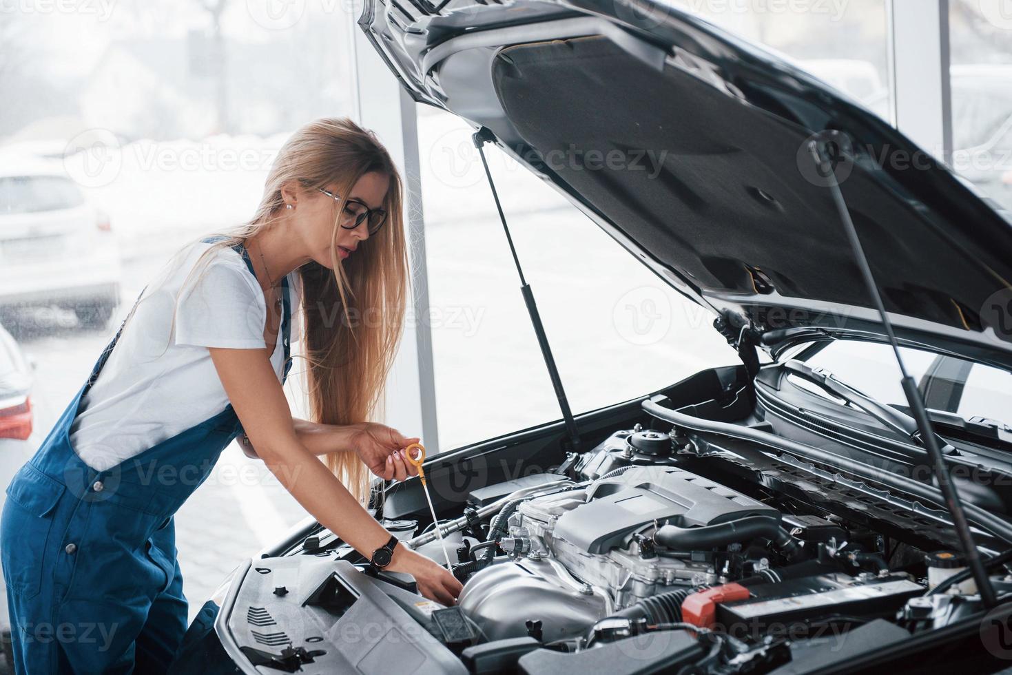 cabelo quase tocou o automóvel. no lindo trabalho. mulher viciada em carro conserta automóvel preto dentro de casa foto