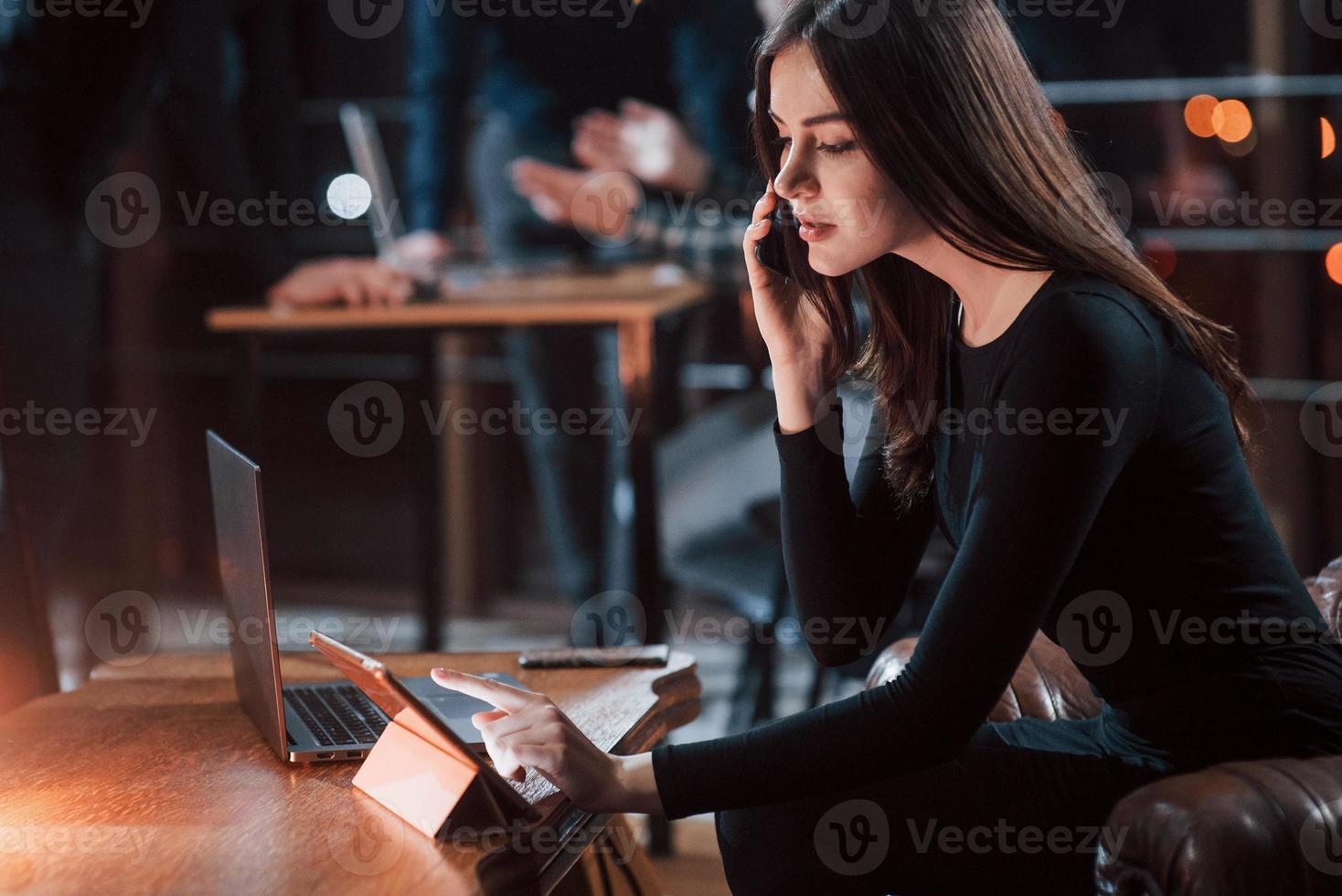 chamando chefe. empresária morena atraente trabalha no escritório à noite foto