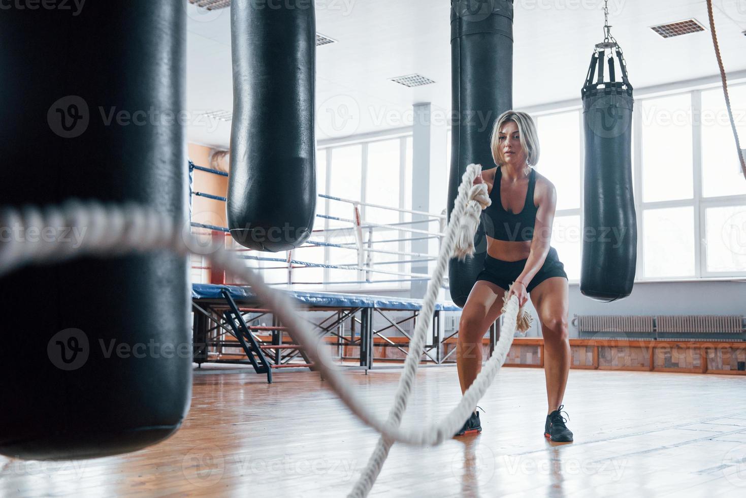 empurrando sacos pendurados ao redor. mulher loira esporte tem exercício com cordas no ginásio. mulher forte foto