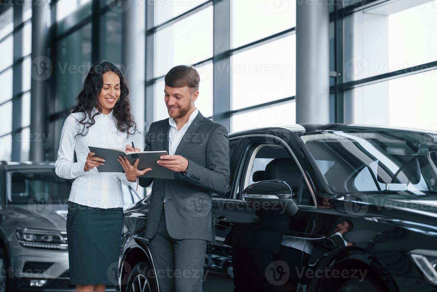 compra quase concluída. cliente do sexo feminino e empresário barbudo elegante moderno no salão do automóvel foto