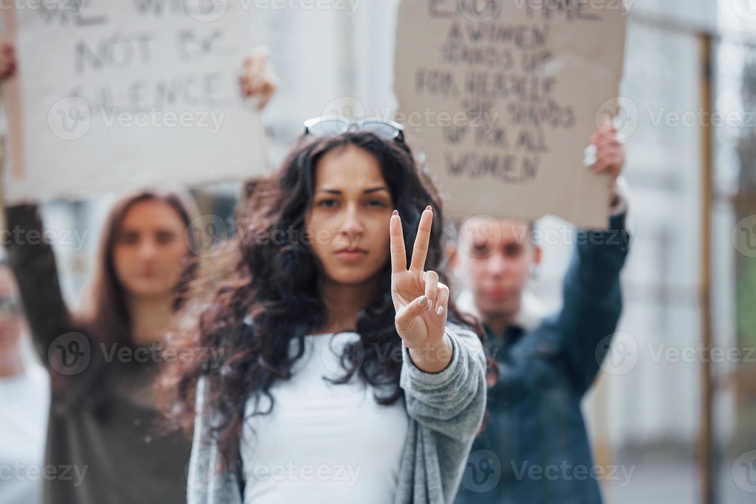 linda morena na frente. grupo de mulheres feministas protestam por seus direitos ao ar livre foto