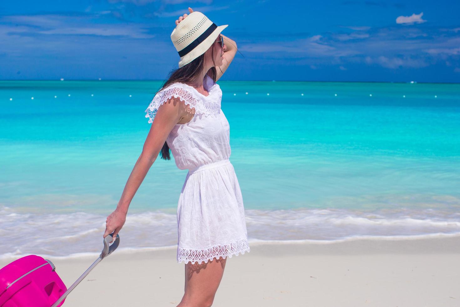 mulher caminhando com sua bagagem na praia foto