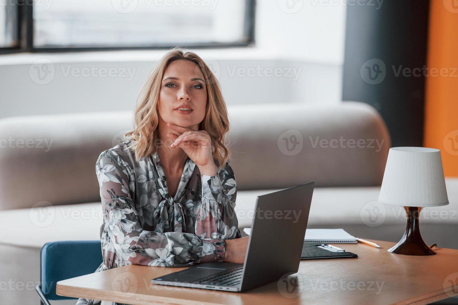 venha à nossa clínica se tiver ansiedade e problemas mentais. mulher de negócios com cabelo loiro encaracolado sentado na sala contra a janela foto