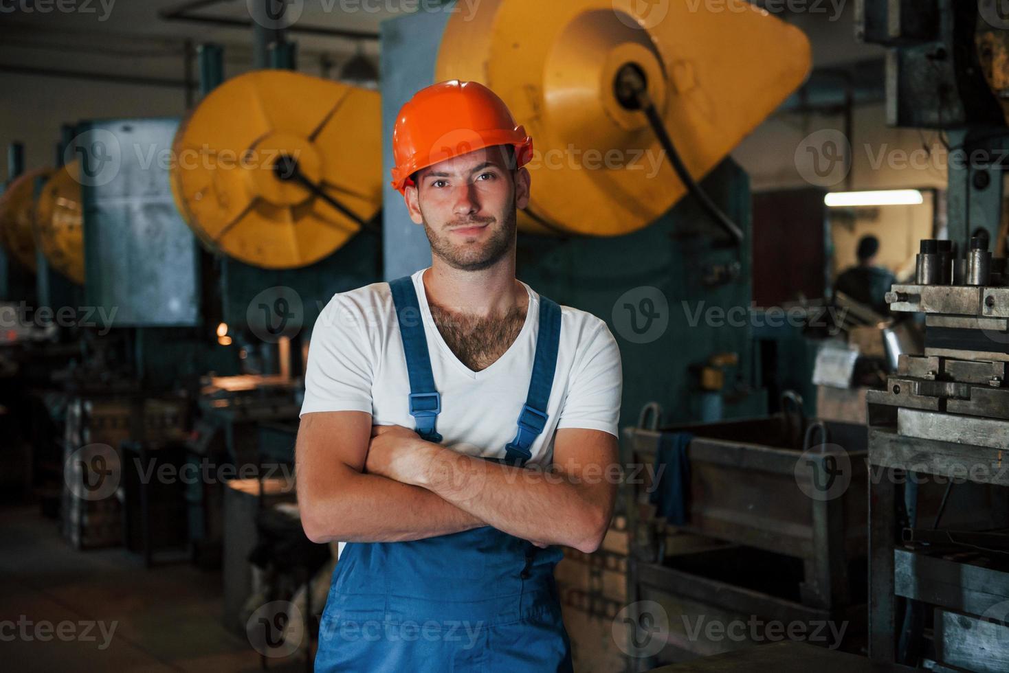 grande máquina de produção atrás. retrato do engenheiro na fábrica metalúrgica no capacete protetor foto