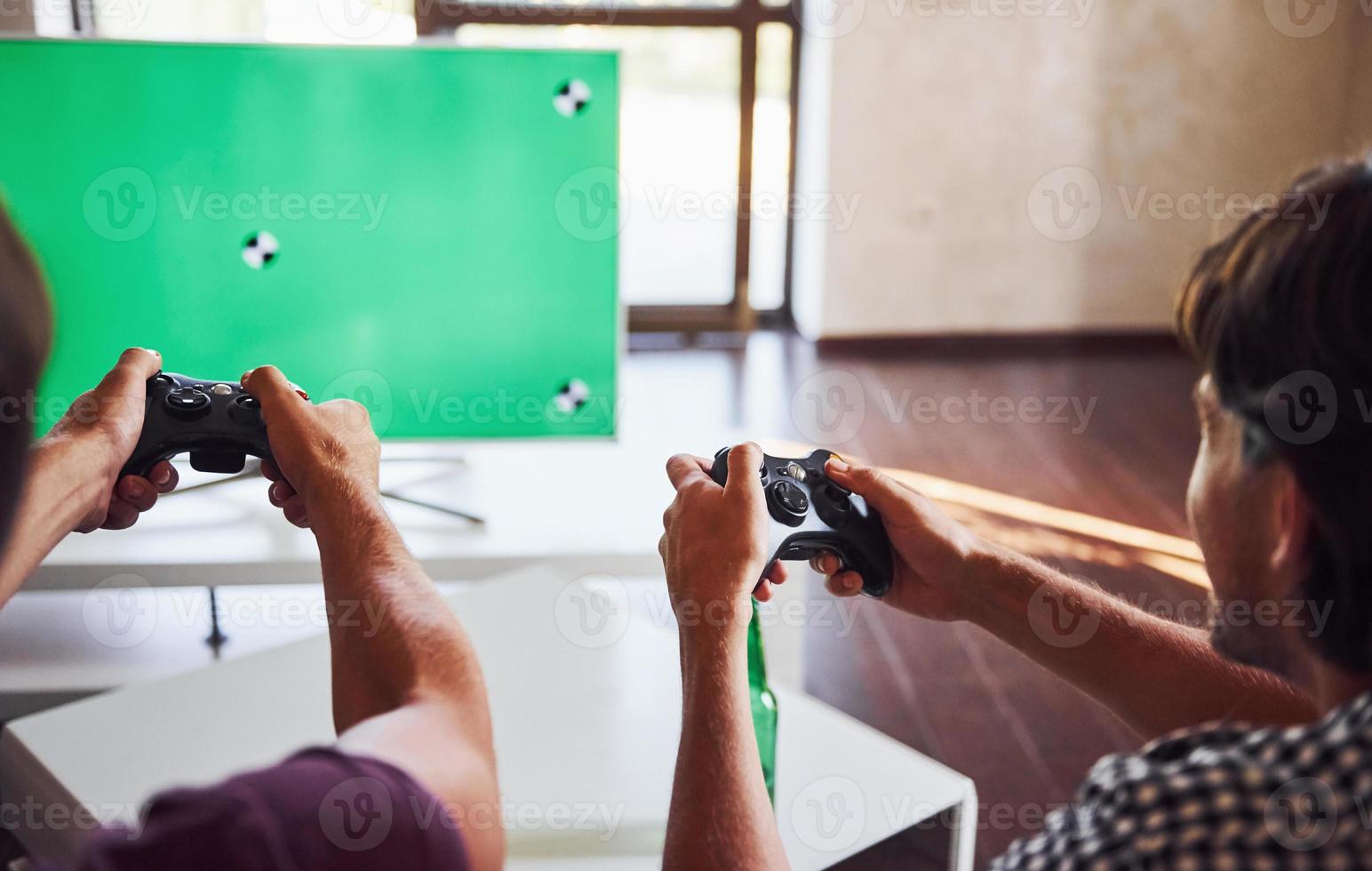 grupo de amigos se diverte jogando jogo de console dentro de casa na sala de estar foto