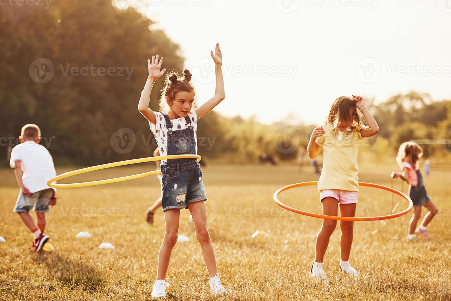 meninas com ferramenta de fitness de círculo. grupo de crianças tem fim de semana ativo no campo foto