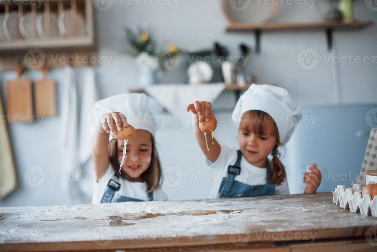 brincando com ovos. filhos de família em uniforme de chef branco preparando comida na cozinha foto