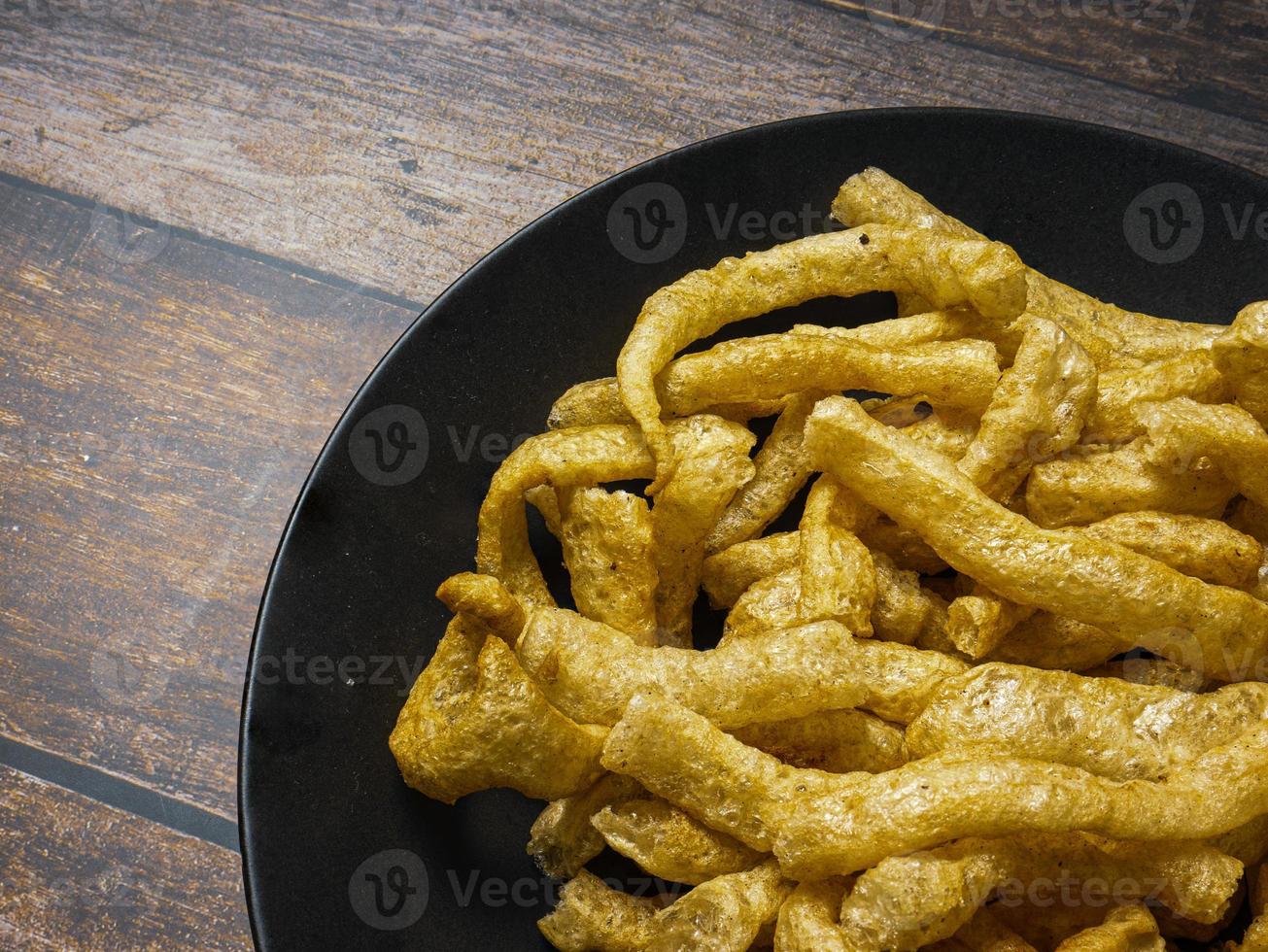 casca de porco em chapa preta na mesa de madeira para o conceito de comida foto