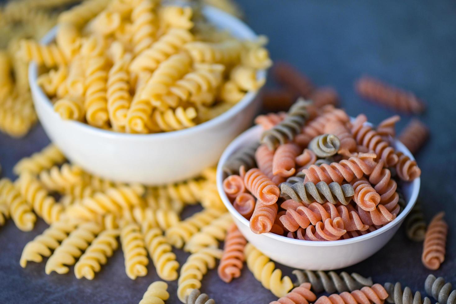 Macarrão cru macarrão no fundo da tigela branca, close-up Macarrão cru macarrão espiral não cozido delicioso fusilli macarrão integral para cozinhar alimentos foto