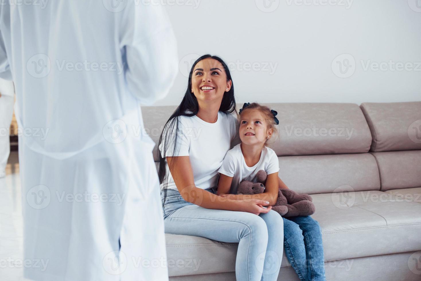 mãe com sua filha fofa está visitando a clínica. ouvindo o médico foto