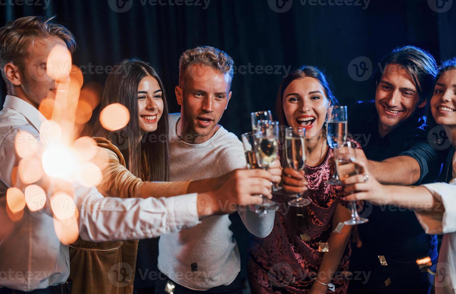 grupo de amigos alegres comemorando o ano novo dentro de casa com bebidas nas mãos foto