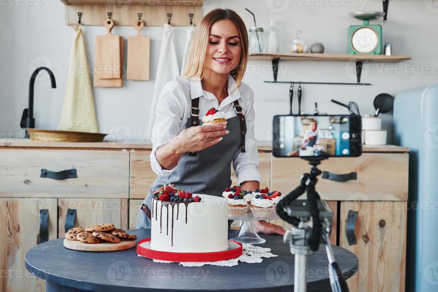 mulher faz deliciosos doces e tortas. processo de gravação por smartphone no tripé foto